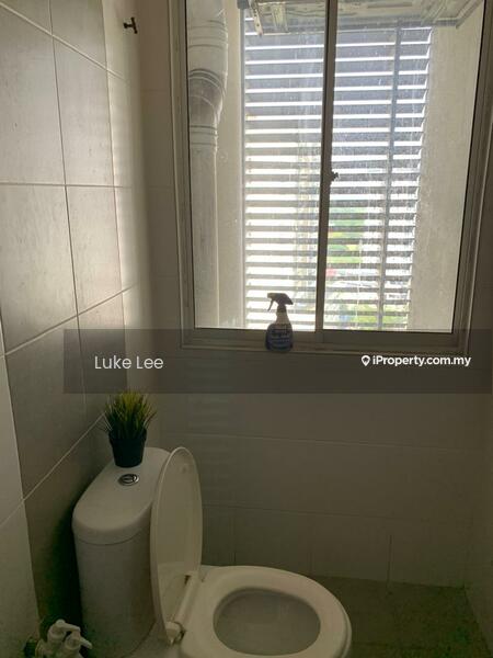 Bathroom features: white ceramic toilet, grey tiled walls, white tiled flooring, window with blinds, cleaning spray bottle on windowsill, small potted plant on windowsill; style: modern; view: city.