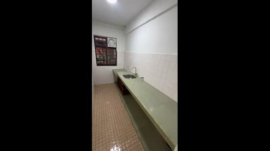 Kitchen features: green countertop, single-bowl stainless-steel sink, wall-mounted faucet, white tiled walls, cream tiled flooring, window with grid pattern, overhead lighting.