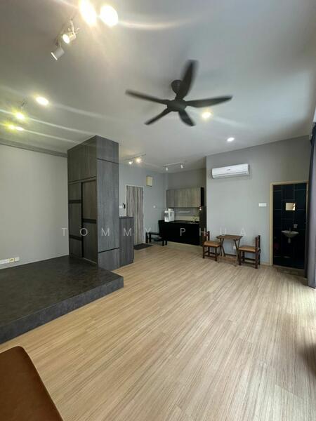 Living features: laminate flooring, grey painted walls, 5-blade ceiling fan, recessed downlights, wall-mounted air conditioning unit, open layout, kitchen area visible, dark cabinetry, countertop, seating area with two chairs, dark feature wall, large windows with natural light; style: modern.