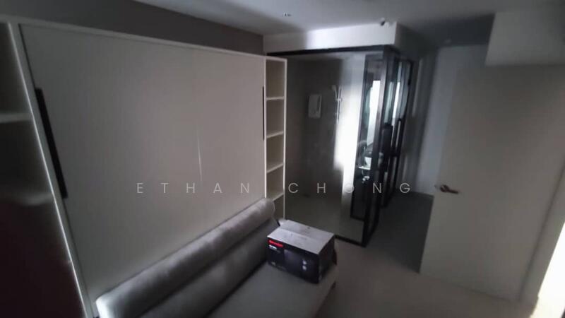 Room features: grey fabric sofa, built-in shelving unit, glass partition, light-colored walls, neutral flooring, small box on the floor, door leading to bathroom, window with natural light; style: modern.
