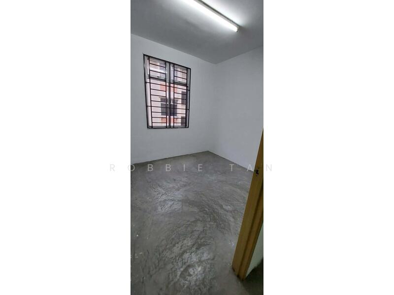 Room features: white painted walls, concrete flooring, single window with metal grille, fluorescent ceiling light, no visible furniture or decor; style: minimalist.