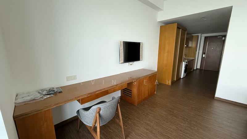 Room features: wooden flooring, white painted walls, wall-mounted TV, wooden desk with storage, grey upholstered chair, built-in cabinetry, doorway leading to another room, window with natural light; style: modern.