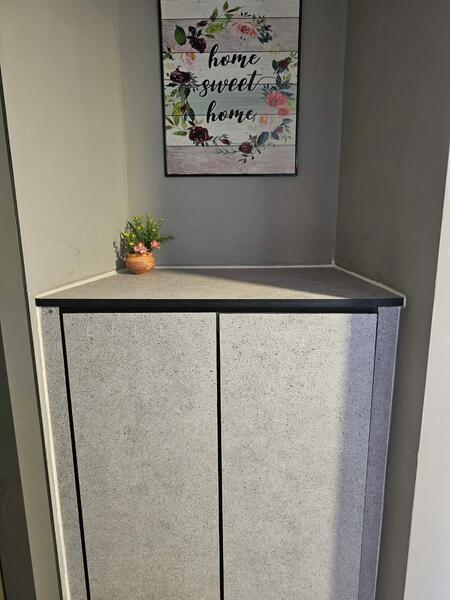 Room features: grey textured cabinetry, black trim, corner cabinet, decorative wall art with floral design, small potted plant, smooth wall surface, neutral wall color; style: modern.