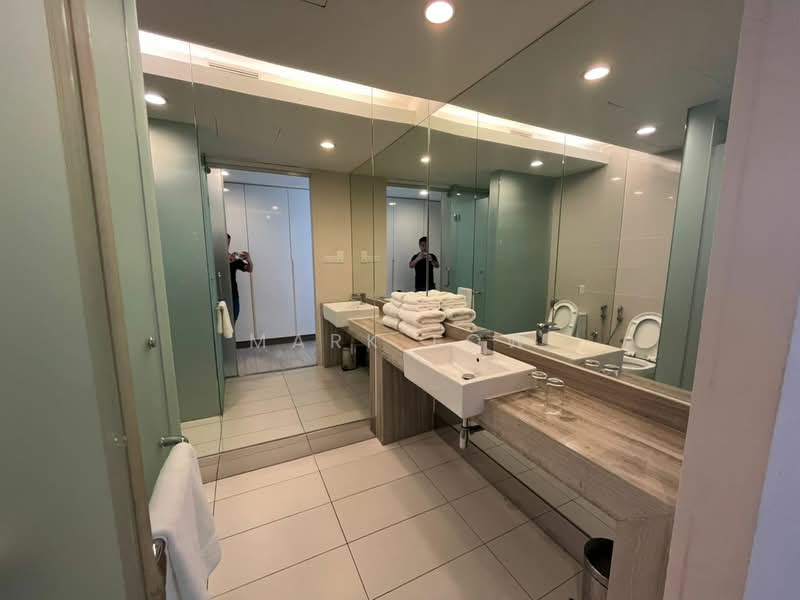 Bathroom features: single-sink vanity with wood cabinet, large mirror, white ceramic sink, chrome basin mixer faucet, white tiled walls, grey tiled flooring, toilet, glass shower enclosure, towel rack, stacked towels, built-in cabinetry, recessed lighting; style: modern.