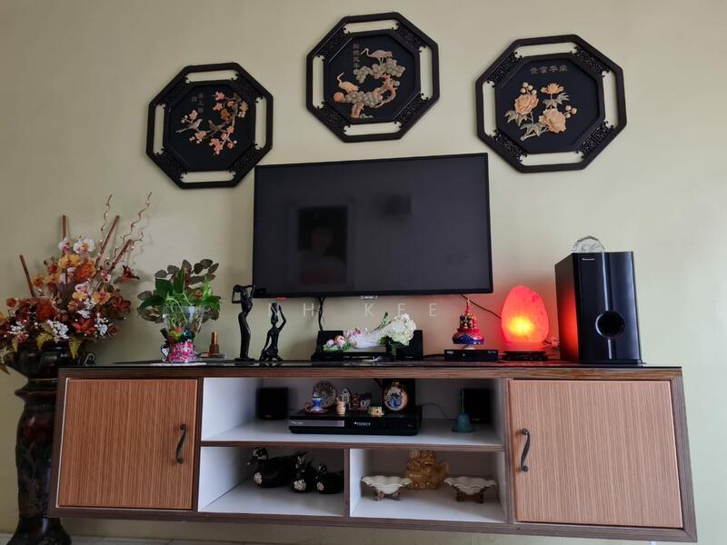 Living features: wooden TV console with open shelving, wall-mounted flat-screen TV, decorative wall art with floral patterns, decorative figurines, table lamp with red light, flower arrangements in vases, black speaker, ceramic decorative items, neutral wall color; style: traditional.