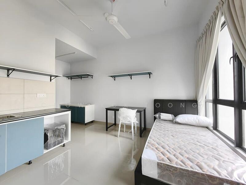 Room features: single bed, white bedding, grey walls, light grey floor tiles, kitchenette with sink, blue cabinetry, open shelving, black study table, white chair, large window, ceiling fan; style: modern.