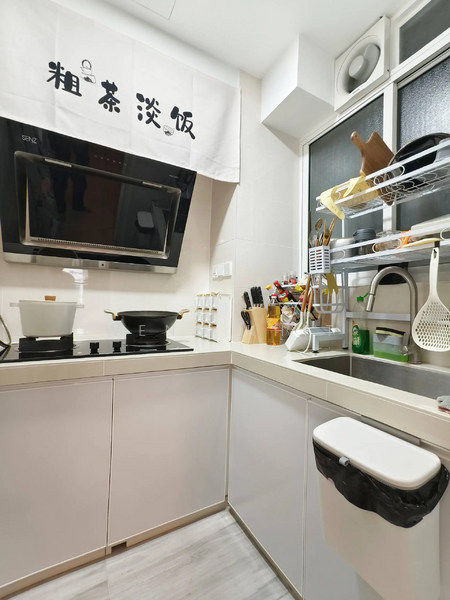 Kitchen features: white cabinetry, stainless-steel sink, chrome pull-down faucet, black induction cooktop, built-in oven, microwave, kitchen utensils holder, open shelving, countertop with backsplash, wall-mounted exhaust hood, garbage bin, window with sheer curtains; style: modern.