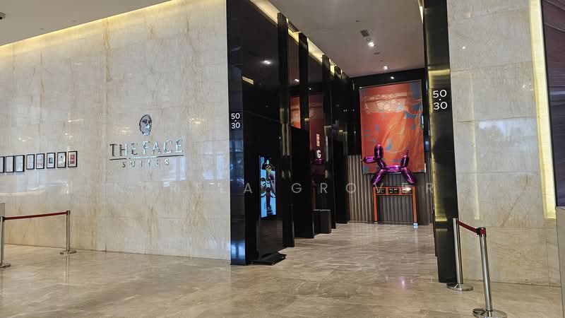 Exterior type: high-rise condominium; features: marble flooring, glass facade, elevators with glass doors, artwork on wall, reception area, illuminated signage, decorative wall panels, red velvet ropes, modern lighting fixtures; style: modern.