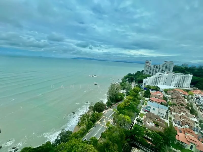 Exterior type: high-rise condominium; features: ocean view, surrounding greenery, adjacent to coastline, multiple buildings in view, road along the coast, residential area nearby; style: modern.