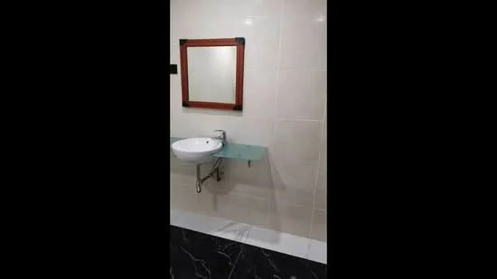 Bathroom features: single-bowl sink, chrome basin mixer faucet, mirror with wooden frame, glass shelf, white tiled walls, black marble flooring, wall-mounted sink, modern design; style: modern.