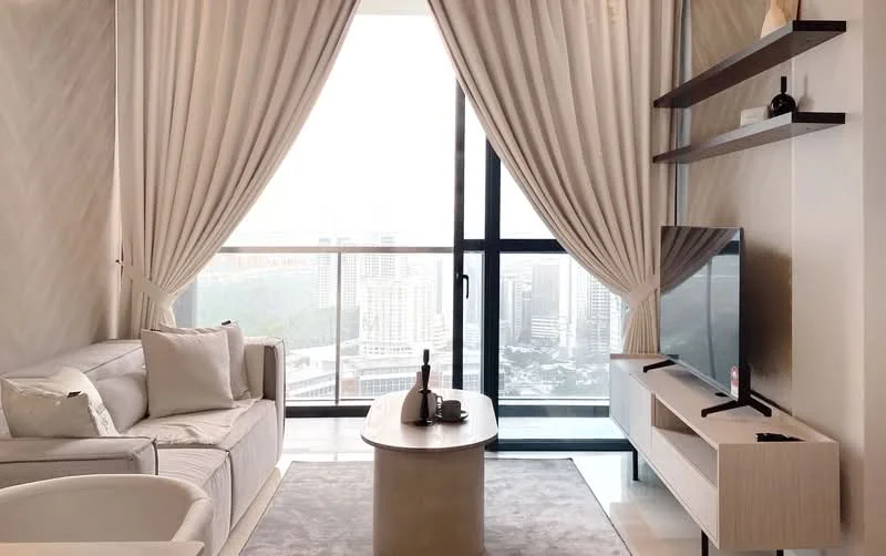 Living features: floor-to-ceiling windows, sheer curtains, 3-seater fabric sofa in light grey, coffee table, wall-mounted TV, TV console, decorative wall shelf, area rug with neutral color, city view, light-colored walls, recessed downlights, decorative items on shelf; style: modern; view: city.