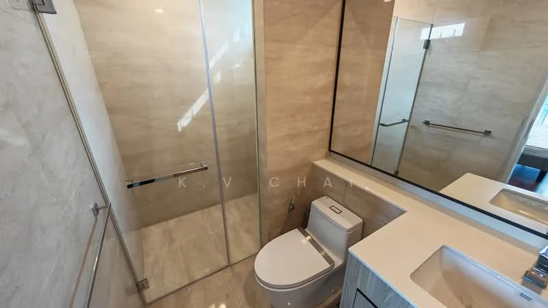 Bathroom features: walk-in shower with glass enclosure, chrome handheld shower, single-sink vanity with white cabinet, white countertop, framed mirror, one-piece toilet, tile cladding on walls, light-colored tile flooring, recessed downlights, grab bar, sliding glass door; style: modern.
