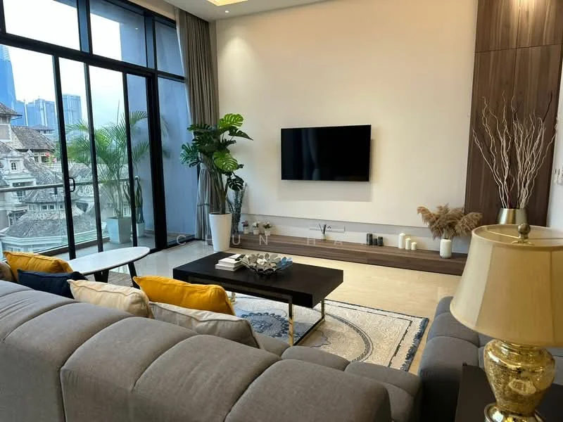 Living features: grey fabric sofa, blue and yellow accent cushions, coffee table with black surface, area rug with geometric pattern, wall-mounted TV, wooden media console, decorative plants, floor-to-ceiling windows, curtains, decorative vase with dried flowers, table lamp with gold base; style: modern; view: city.