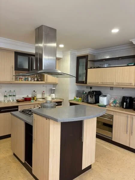 Kitchen features: island kitchen with curved countertop, stainless-steel range hood, built-in oven, 4-burner gas hob, dark wood cabinetry, light wood cabinetry, granite countertop, ceramic tile backsplash, recessed downlights, microwave, coffee machine, water bottles on countertop, kettle, dishwasher; style: modern.
