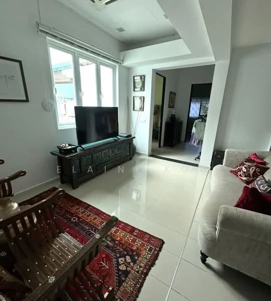 Living features: white painted walls, glossy tile flooring, floor-to-ceiling windows, black TV console, wall-mounted TV, sofa in light grey fabric, decorative cushions in red, area rug with geometric pattern, wooden rocking chair, framed artwork on walls; style: modern. Room features: doorway leading to another room, clothing visible in doorway.