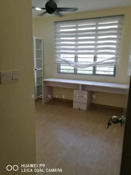 Room features: light wood laminate flooring, yellow painted walls, large window with horizontal blinds, ceiling fan, built-in desk with pink cabinetry, white shelving unit, neutral decor; style: modern; view: city.