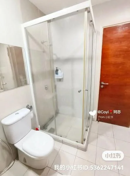 Bathroom features: glass shower enclosure, chrome shower head, white toilet, wall-mounted soap dispenser, mirror with frame, light-colored wall tiles, light-colored floor tiles, wooden door; style: modern.