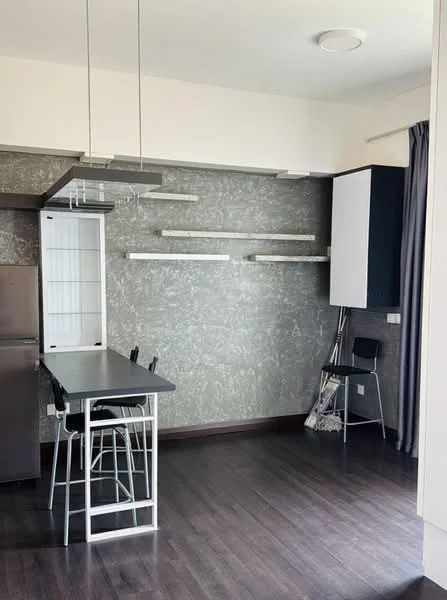 Kitchen features: grey textured wall, dark wood flooring, black countertop, stainless-steel fridge, open shelving, hanging light fixtures, bar stools, white cabinetry, floor-to-ceiling window treatments; style: modern.