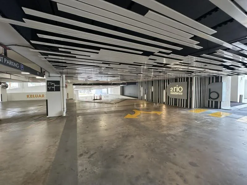 Exterior type: parking deck; features: concrete flooring, striped ceiling design, illuminated ceiling panels, marked parking spaces, exit signage, decorative wall with branding, open-air structure, visible natural light, painted directional arrows; style: modern.