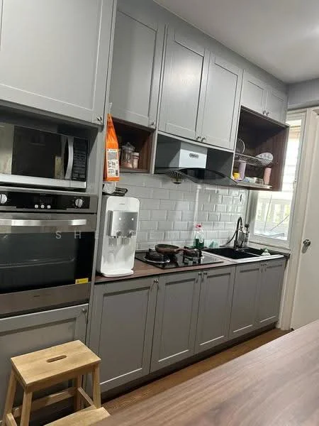 Kitchen features: grey cabinetry, white subway tile backsplash, stainless-steel sink, chrome pull-down faucet, built-in oven, freestanding range oven, microwave, water dispenser, wood countertop, stool, window with natural light; style: modern.