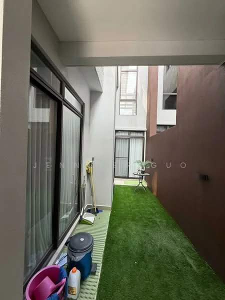 Room features: green artificial grass flooring, white painted walls, large windows with sheer curtains, cleaning supplies visible, plastic storage containers, small outdoor table, narrow corridor layout; style: modern.