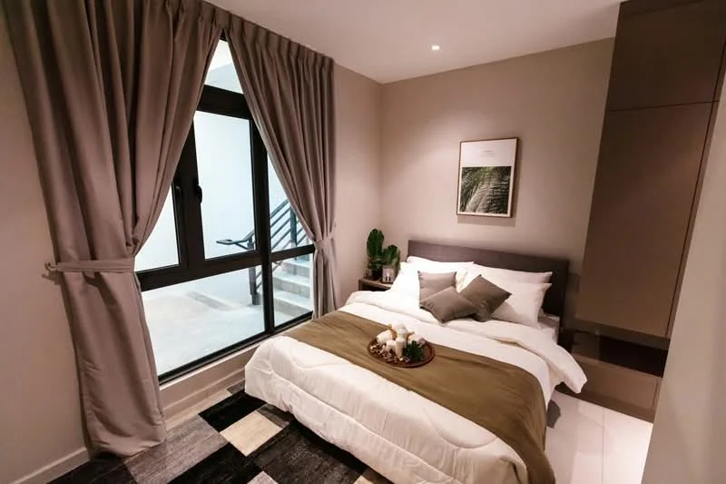 Bedroom features: queen-size bed with white bedding, upholstered headboard, decorative pillows in grey and beige, nightstand with decorative items, framed artwork on the wall, floor-to-ceiling window, sheer curtains, dark wood flooring, built-in wardrobe, area rug with geometric pattern; style: modern; view: outdoor stairs.