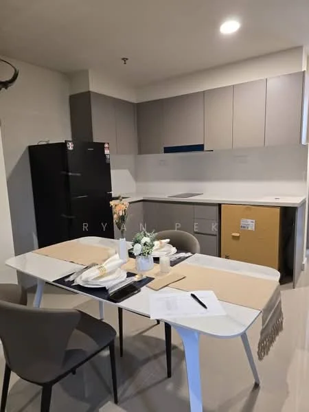 Kitchen features: grey and beige cabinetry, white countertop, stainless-steel sink, built-in stove, black refrigerator, table with white surface, 4 dining chairs, decorative vase with flowers, notepad and utensils on table, wall-mounted cabinets, open shelving, tile flooring; style: modern.