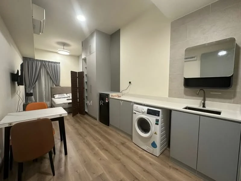 Room features: light wood laminate flooring, white painted walls, grey cabinetry, white countertop, single-bowl stainless-steel sink, chrome pull-down faucet, built-in refrigerator, front-load washing machine, wall-mounted mirror, recessed ceiling lights, dining table for two, orange upholstered dining chairs, grey curtains, bed visible in background; style: modern.