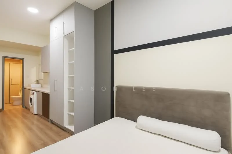 Bedroom features: queen-size bed with upholstered headboard, light-colored bedding, built-in wardrobe with sliding doors, white washing machine, wooden flooring, recessed ceiling lights, neutral wall color, decorative wall paneling; style: modern. Bathroom features: glass shower enclosure, white toilet, vanity with sink, neutral tile flooring, mirror above vanity.