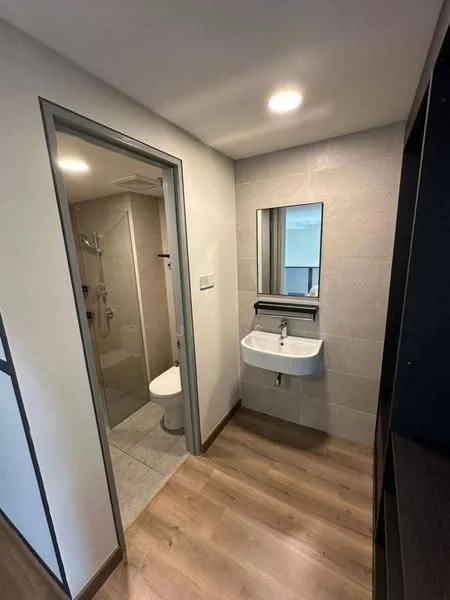 Bathroom features: single-sink wall-mounted vanity, chrome basin mixer faucet, framed mirror, walk-in shower with glass enclosure, toilet, grey tile flooring, light grey wall tiles, recessed downlights, wooden flooring at entrance, sliding door, shower head, towel rail; style: modern.