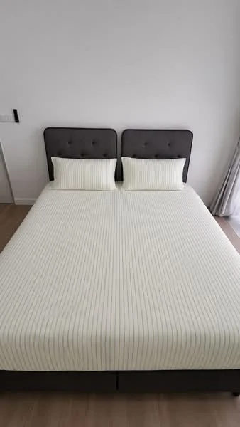 Bedroom features: king-size bed, upholstered headboard in grey, striped bedding in cream, two matching pillows, wooden flooring, white painted walls, curtains in light fabric; style: modern.