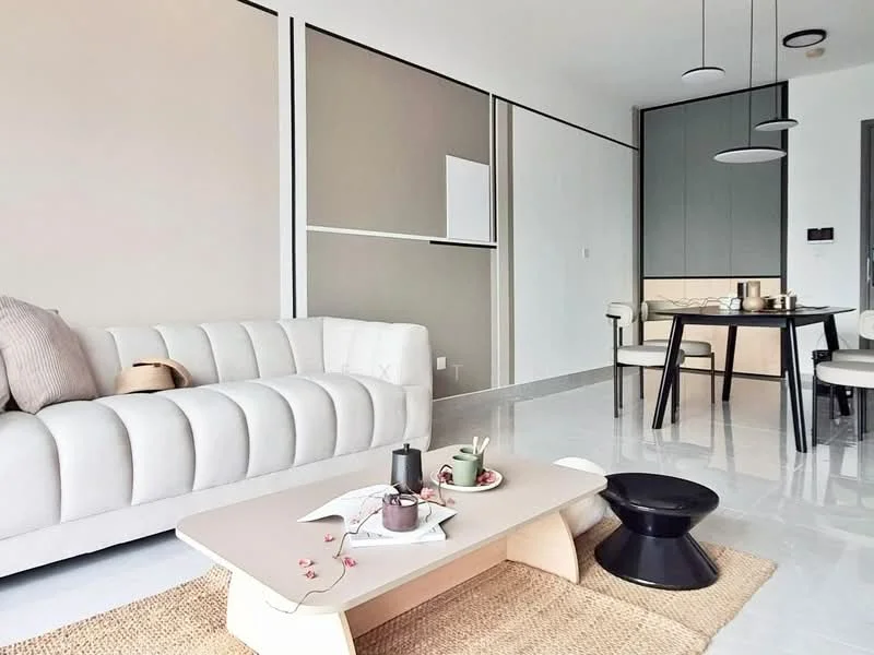Living features: 3-seater fabric sofa in cream, coffee table with minimalist design, black accent stool, area rug with natural texture, white walls, grey accent wall, recessed downlights, pendant lights, dining table with 4 chairs, built-in cabinetry in grey, polished tile flooring; style: modern.