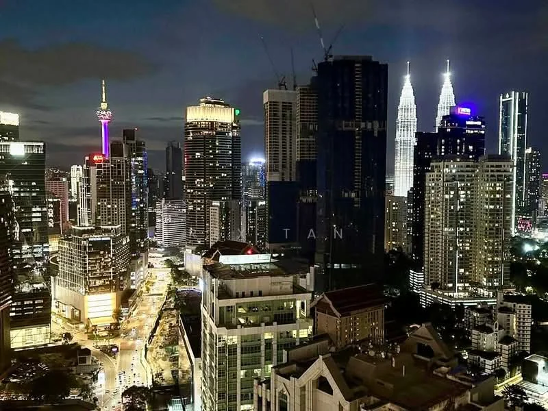 Exterior type: high-rise condominium; features: city skyline view, nighttime illumination, prominent towers including Petronas Twin Towers, various high-rise buildings, urban landscape, streetlights along the road; style: modern.