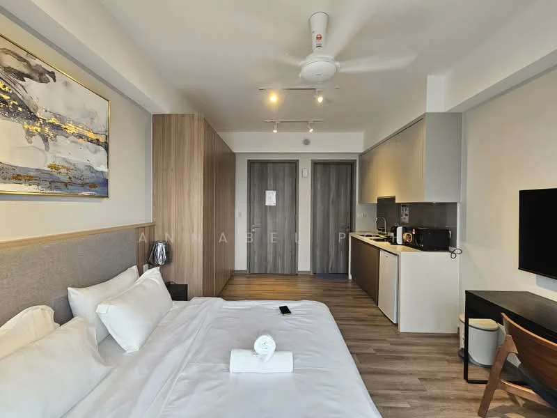 Bedroom features: king-size bed with white bedding, wooden headboard, wall-mounted TV, ceiling fan with light, wooden flooring, built-in wardrobe with sliding doors, kitchenette with microwave, kitchen cabinets, countertop with sink, small dining table with chair, decorative artwork on wall, window with natural light; style: modern.