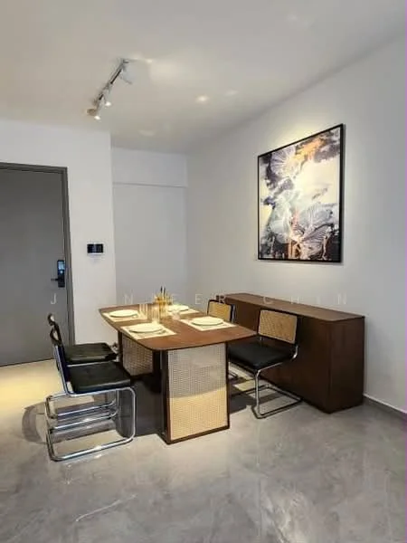 Dining features: dining table with rattan detailing, 4 black dining chairs with chrome legs, framed artwork on wall, grey marble flooring, white painted walls, recessed ceiling lights, wall-mounted intercom panel, door leading to hallway; style: modern.