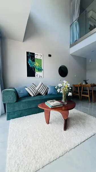 Living features: green fabric sofa, striped throw pillows, round wooden coffee table, white area rug, framed artwork on wall, decorative mirror, floor-to-ceiling windows with sheer curtains, grey painted walls, recessed lighting, dining area visible in background; style: modern.