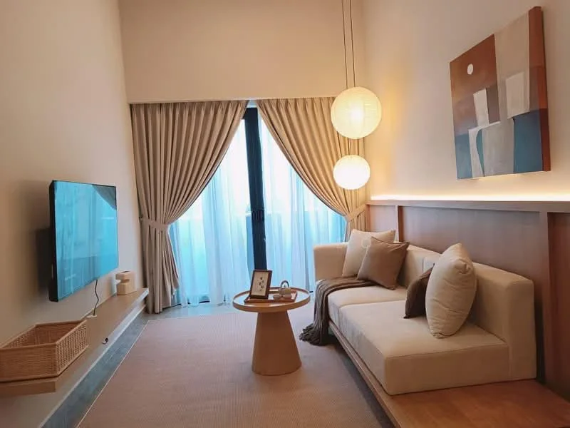 Living features: sofa in cream fabric, round wooden coffee table, wall-mounted TV, floor-to-ceiling windows, sheer curtains, decorative wall art, pendant lighting, light-colored carpet, wood paneling on wall, basket for storage; style: modern; view: city.