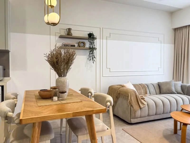 Living features: beige fabric sofa, wooden coffee table, round wooden dining table, upholstered dining chairs, decorative vase with dried flowers, shelf with decorative items, neutral wall color, curtains, area rug, wall paneling; style: modern.