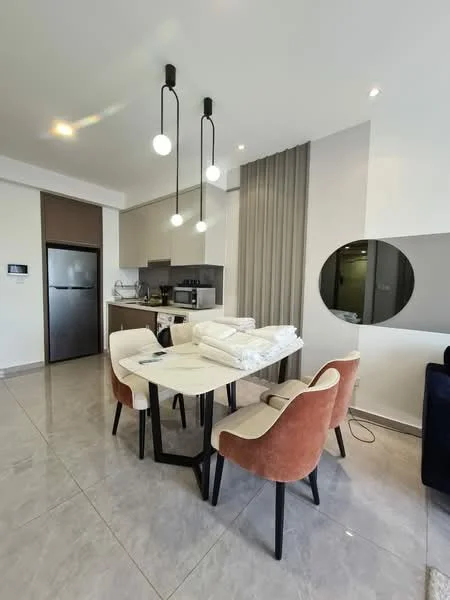 Dining features: round dining table, 4 upholstered dining chairs in beige, pendant lighting with three globes, grey accent wall, marble tile flooring, built-in kitchen cabinetry, stainless-steel fridge, kitchen countertop, open layout to kitchen, decorative mirror on wall; style: modern.