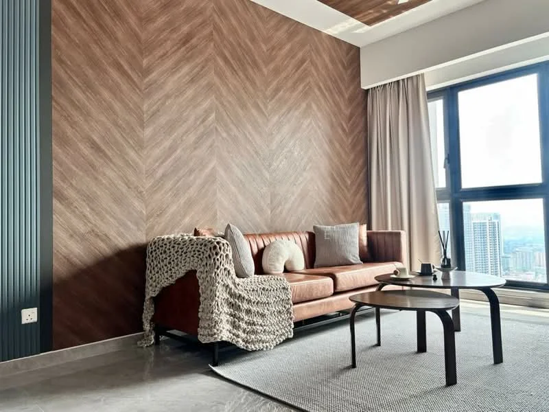 Living features: brown leather sofa, textured throw blanket, decorative cushions, wood herringbone accent wall, light grey area rug, round coffee table, floor-to-ceiling windows, curtains, polished stone flooring, recessed ceiling lights; style: modern; view: city.