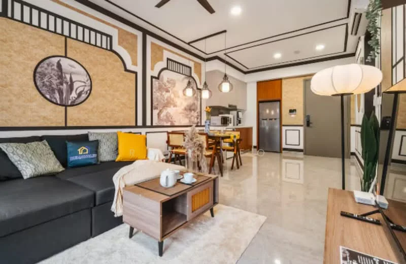 Living features: grey fabric sofa, wood coffee table, area rug, wall-mounted TV, pendant lighting, decorative wall panels with floral design, ceiling fan with light, decorative plants, wooden side table, dining table with four chairs, kitchenette with built-in cabinets, stainless-steel fridge; style: modern.
