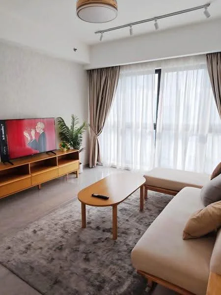 Living features: sofa with beige upholstery, wooden coffee table, TV console in light wood, wall-mounted TV, area rug with neutral tones, floor-to-ceiling windows, sheer curtains, potted plant, recessed lighting, ceiling light fixture; style: modern; view: city.