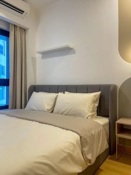 Bedroom features: queen-size bed with grey upholstered headboard, white bedding, light grey throw blanket, nightstand with drawer, table lamp on nightstand, floor-to-ceiling window with sheer curtains, light wood flooring, wall-mounted air conditioning unit, white painted walls, shelf above the bed; style: modern; view: city.