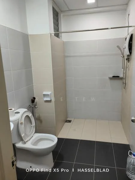 Bathroom features: white ceramic toilet, shower area with glass partition, chrome handheld shower head, wall-mounted shower mixer, white wall tiles, grey floor tiles, built-in shelf in shower area, towel rack, light fixture in ceiling, toilet paper holder; style: modern.