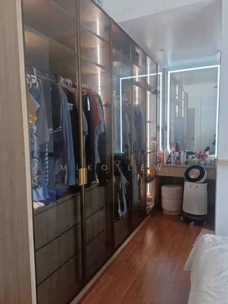 Room features: built-in wardrobe with glass doors, wooden cabinetry, hanging space for clothes, drawers in lower section, backlit mirror, wooden flooring, decorative items on countertop, clothing on hangers; style: modern.