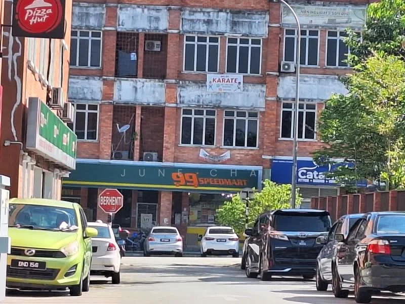 Exterior type: shophouse; features: red brick facade, ground floor retail space, signage for 99 Speedmart, signage for Pizza Hut, signage for Karate studio, multiple storeys, windows with metal grilles, street view with parked cars, trees lining the street; style: modern.