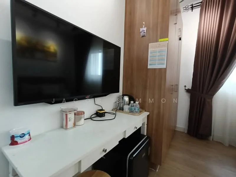 Room features: wall-mounted flat-screen TV, white desk with drawers, wooden stool, mini fridge, kettle, bottled water, cup, wooden cabinet, curtains, laminate flooring, window with natural light; style: modern.