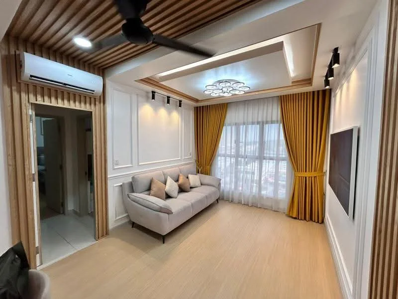 Living features: 3-seater fabric sofa in light grey, decorative cushions, wooden feature wall with horizontal slats, recessed ceiling with LED lighting, chandelier with multiple bulbs, floor-to-ceiling windows with sheer curtains, yellow drapes, light wood flooring, wall-mounted TV, air conditioning unit; style: modern; view: city. Room features: white painted walls, doorway leading to another room.