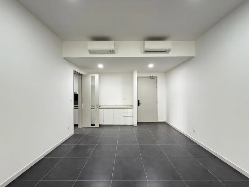 Room features: white painted walls, grey floor tiles, 2 wall-mounted split AC units, door leading to kitchen area, door leading to main entrance, recessed lighting, open layout, no visible furniture; style: modern.