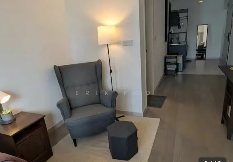 Room features: grey wingback armchair, small black hexagonal side table, wooden side table, table lamp with fabric shade, light wood flooring, white painted walls, doorway leading to another room, recessed ceiling lights; style: modern.